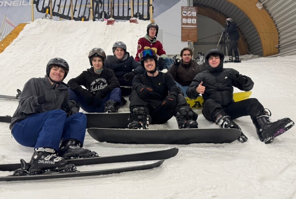 Group photo of the group of friends in class during an indoor snowboarding activity, capturing the close bond and fun of the moment.